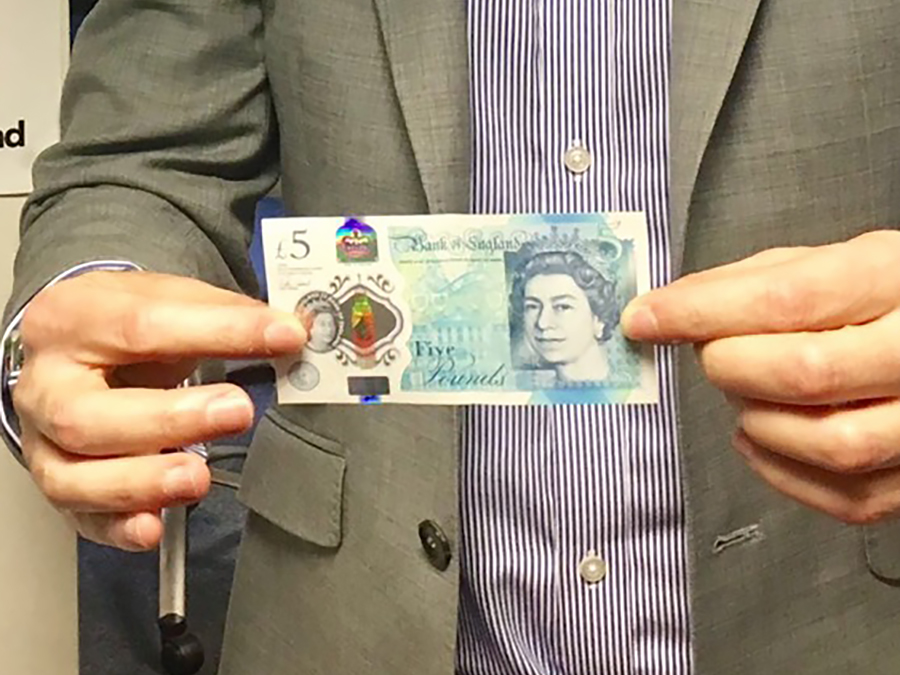 man holding up a five pound note