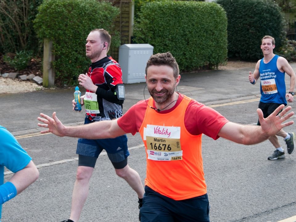 Man running. He's smiling and has his hands in the air