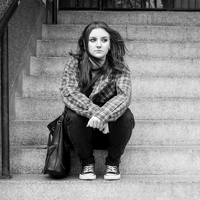 A stock photo of a woman used to illustrate a Launchpad case study. She is sat outside on concrete steps.