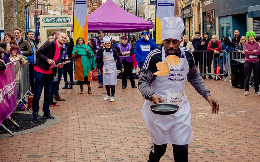 Man flipping pancake as he takes part in the Launchpad Pancake Race in Reading town centre